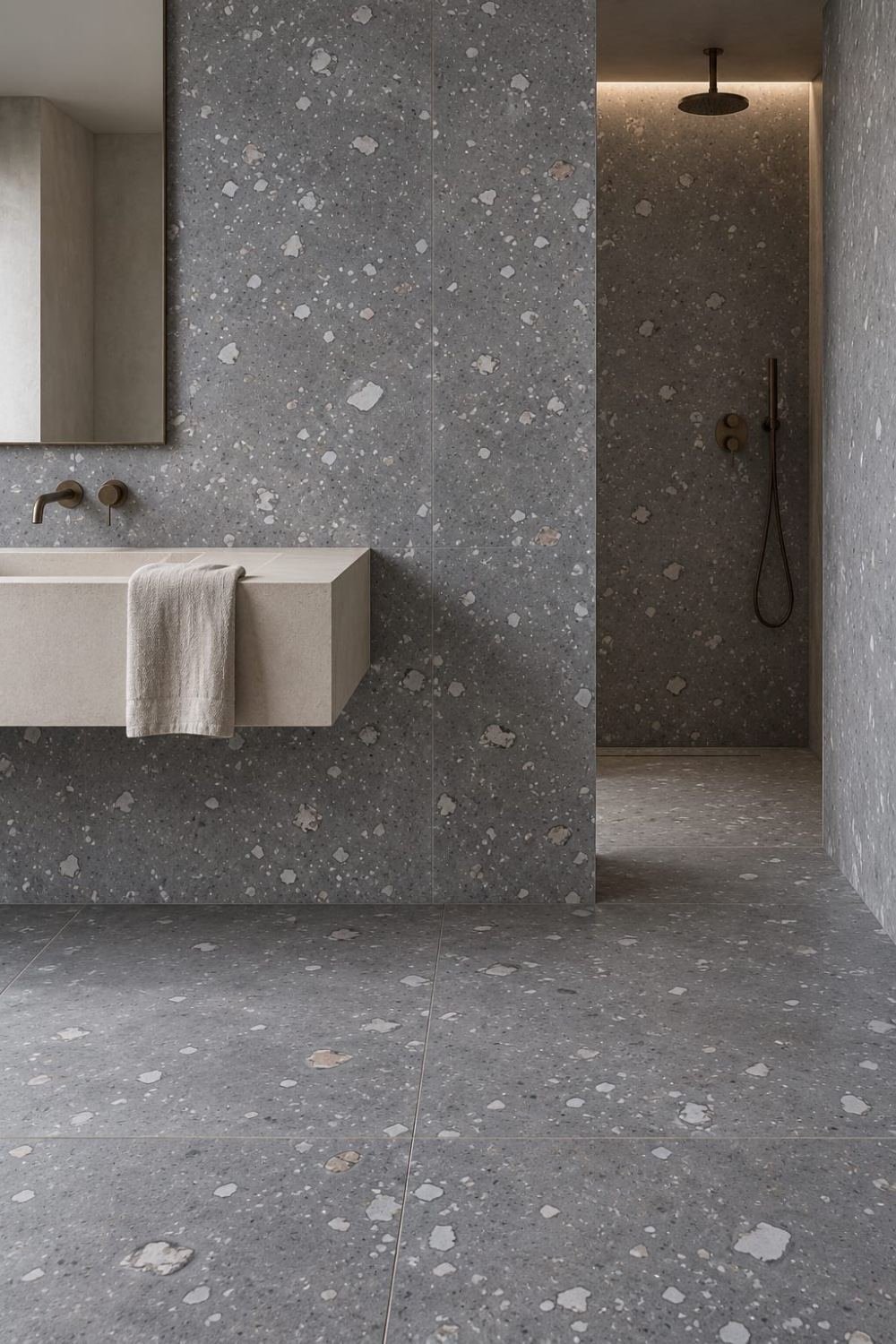 Superficie in agglomerato grigio con inclusioni chiare estesa a pareti e pavimento di un ambiente bagno