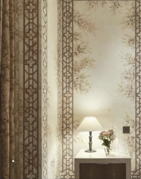 Carta da parati dipinta a mano installata nell’ambiente, con cornici geometriche e foliage