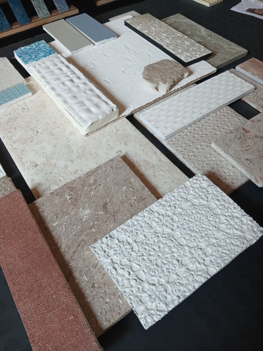 Vista angolata di campioni con rilievi, impasti, resinature e differenti finiture superficiali