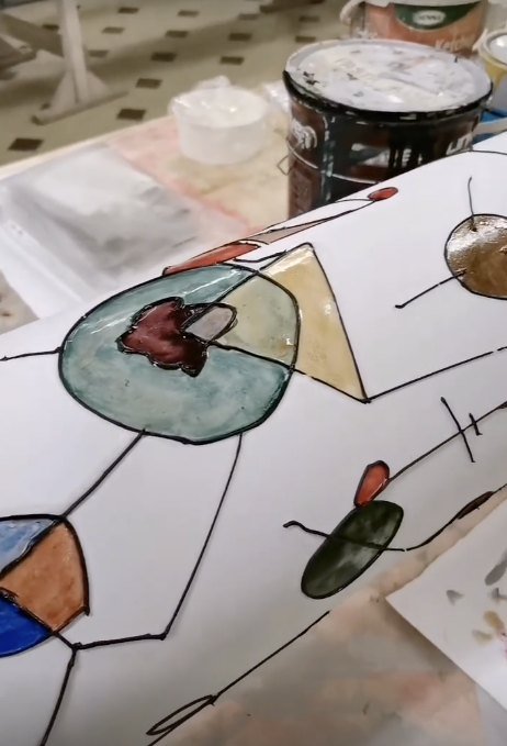 Lampada in carta durante la lavorazione, con campiture colorate e linee nere dipinte a mano